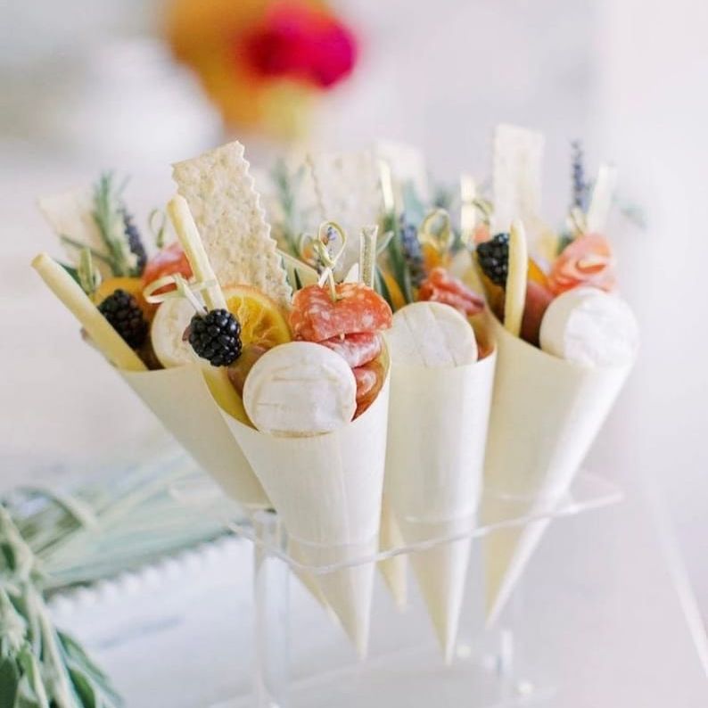 Bamboo cones filled with fruits, cheese, and charcuterie on display