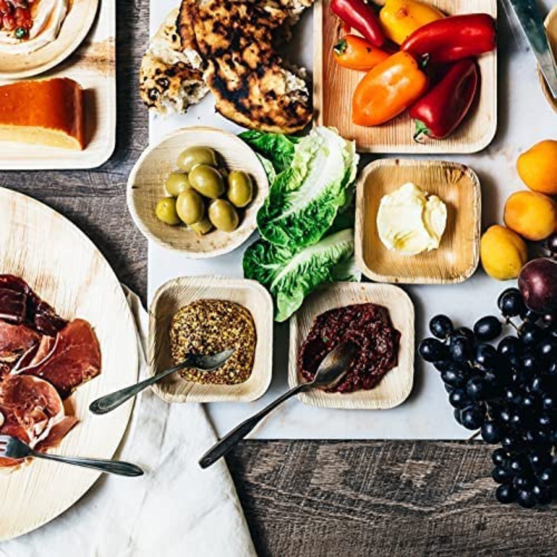 Charcuterie and fruit spread styled with assorted bamboo plates