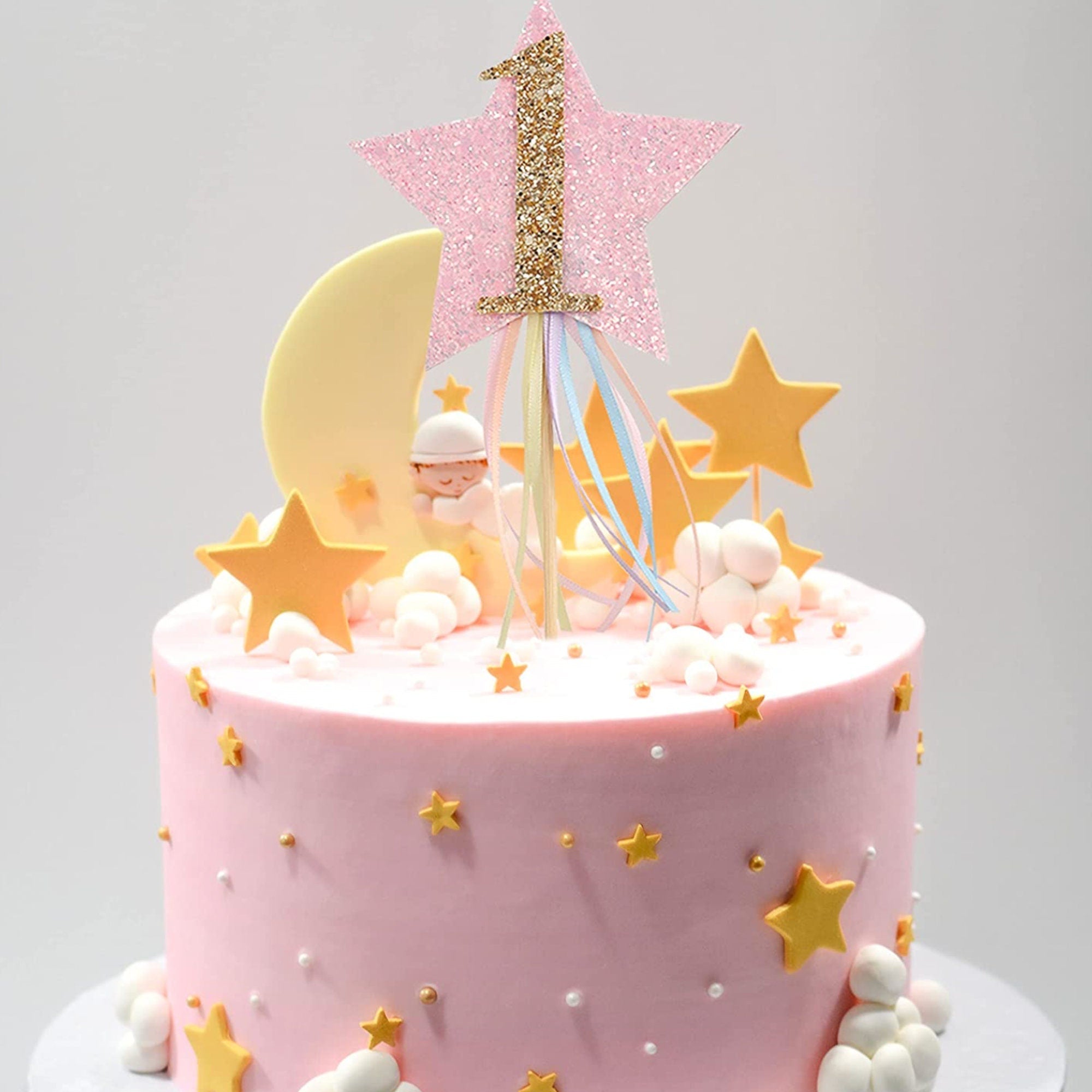1st birthday cake decorated with glittery gold star cake toppers and pink frosting