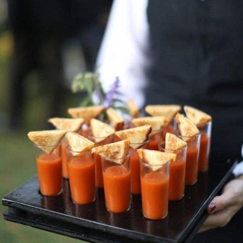 Mini acrylic soup cups arranged on a black tray, elegantly presented with soups, showcasing functionality and sophistication for upscale events.