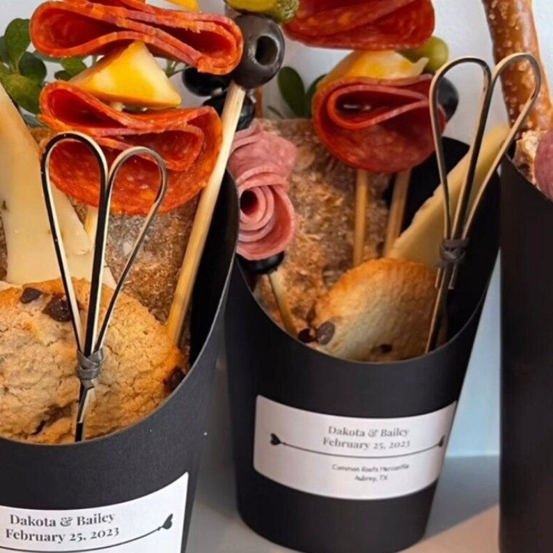Black charcuterie cups filled with meats and breadsticks at event.