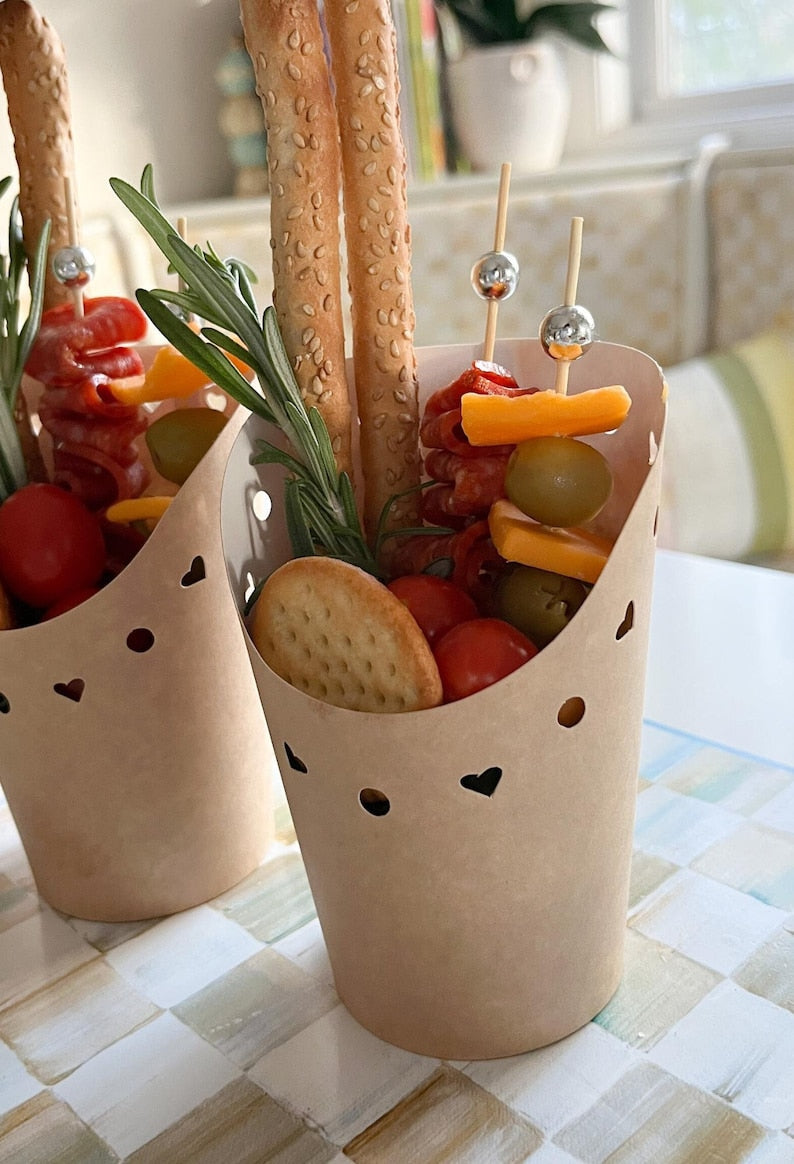 Brown charcuterie cups filled with appetizers using fancy toothpicks