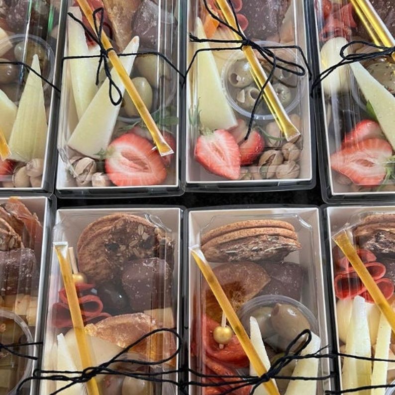 Row of disposable charcuterie boxes arranged for weddings and parties.