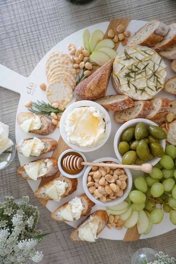 Charcuterie board with honey dipper and assorted cheeses, nuts, and fruits