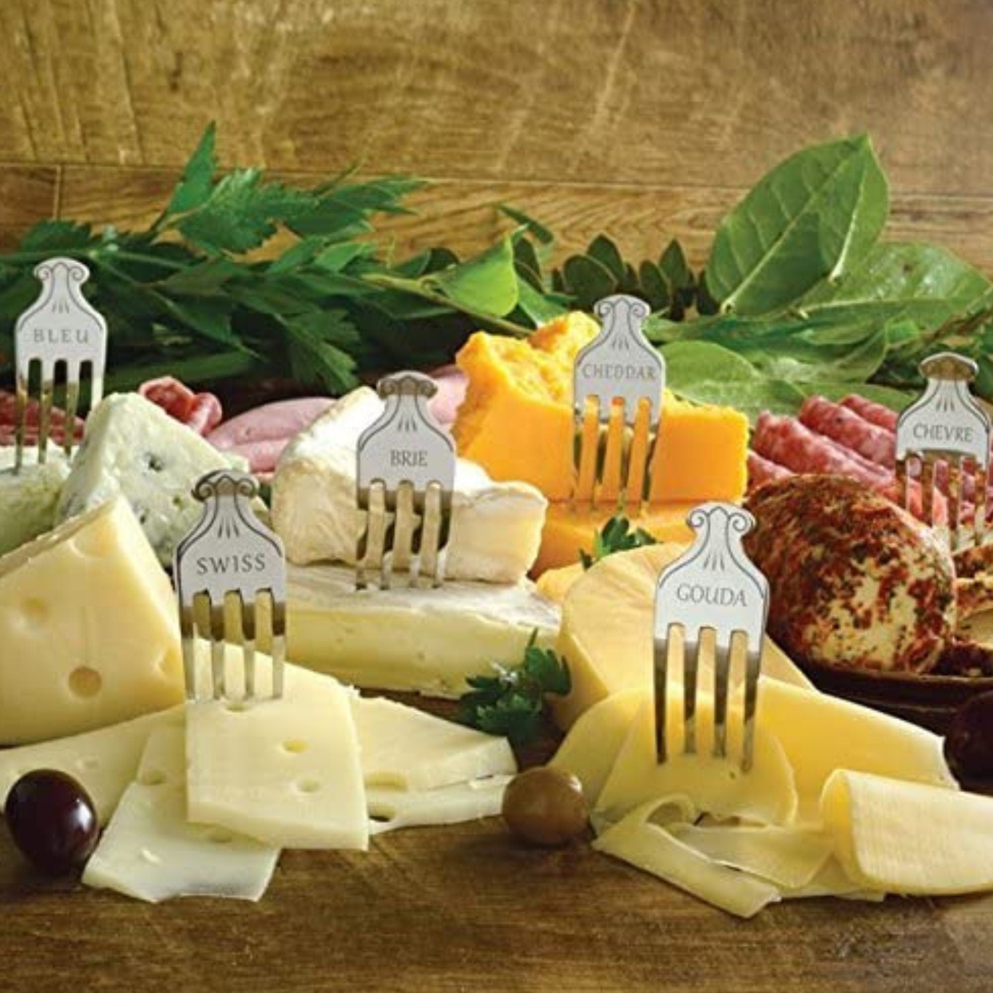 Group shot of assorted cheeses on a charcuterie board with multiple stainless steel cheese markers