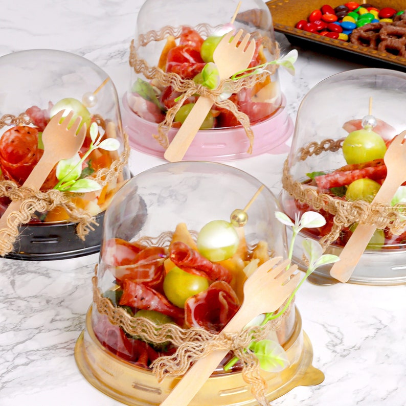 Charcuterie domes displayed at a wedding, filled with appetizers and sealed with dome lids.
