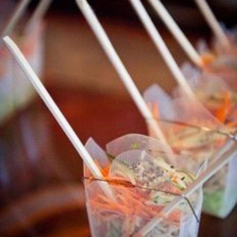 Clear Chinese take out box with noodles and wooden chopsticks for party appetizers.