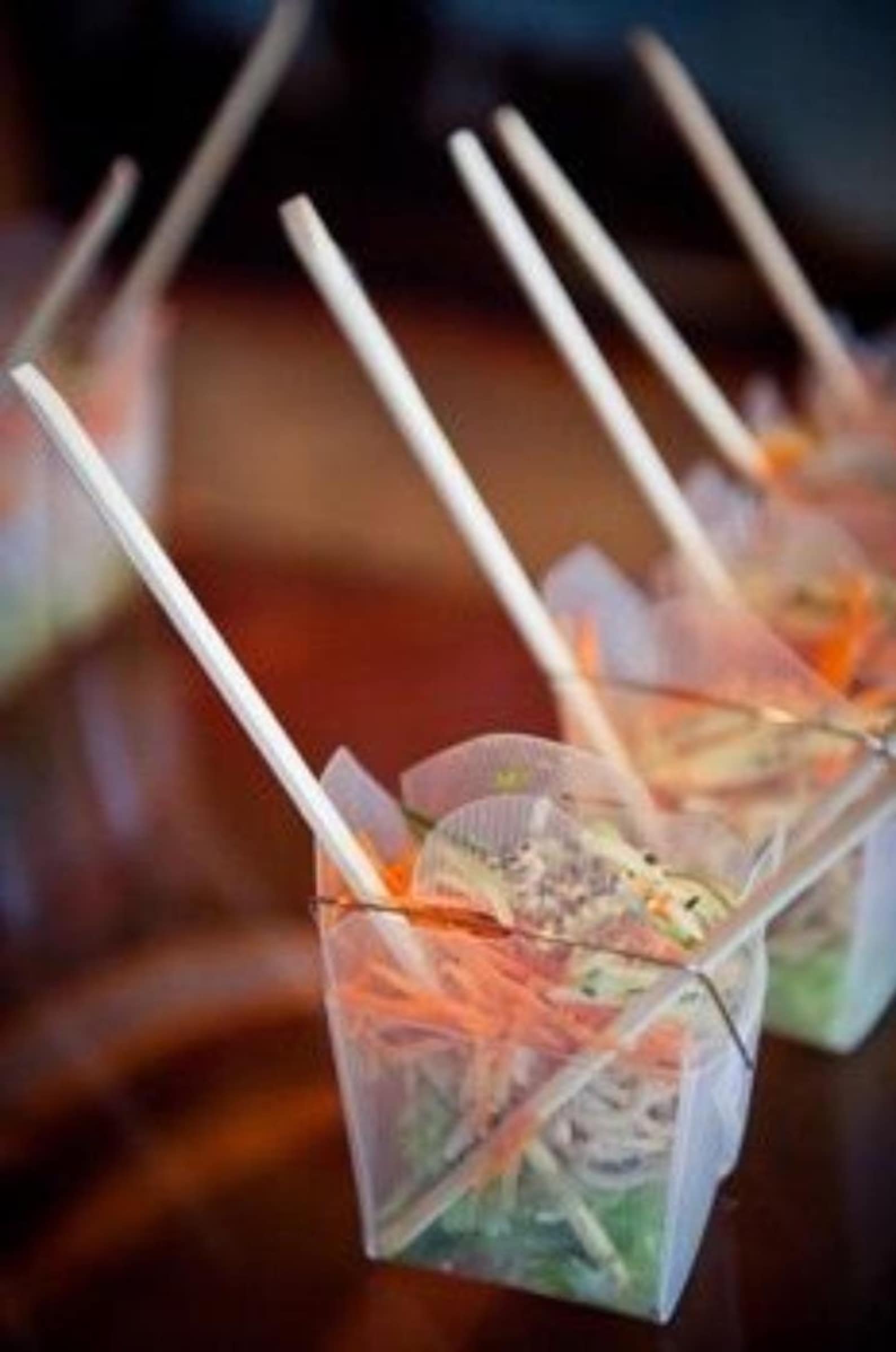 Clear Chinese take out box with noodles and wooden chopsticks for party appetizers.
