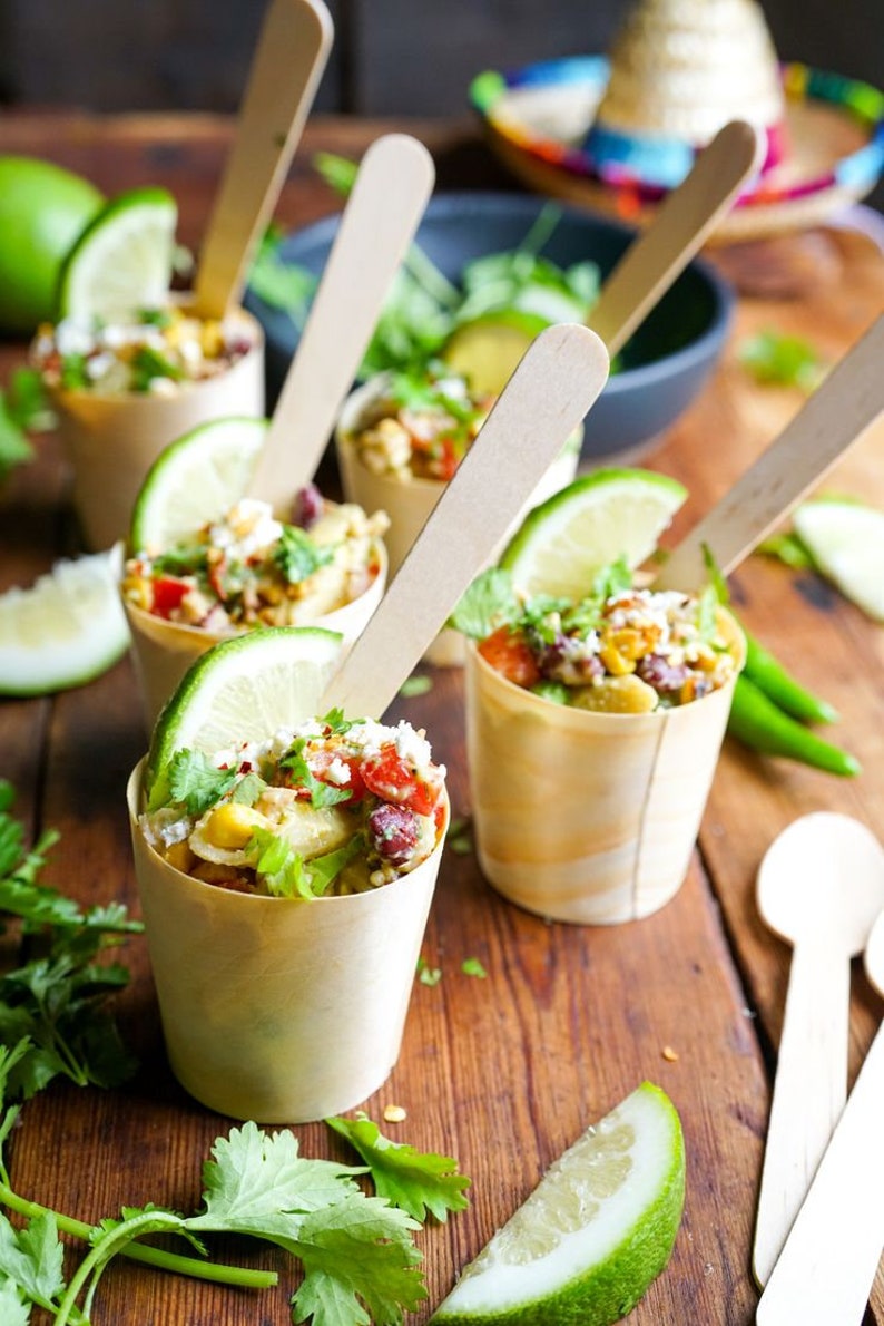 Close-up of charcuterie cup with meat, cheese, and crackers. Individual disposable wooden cone for catering.
