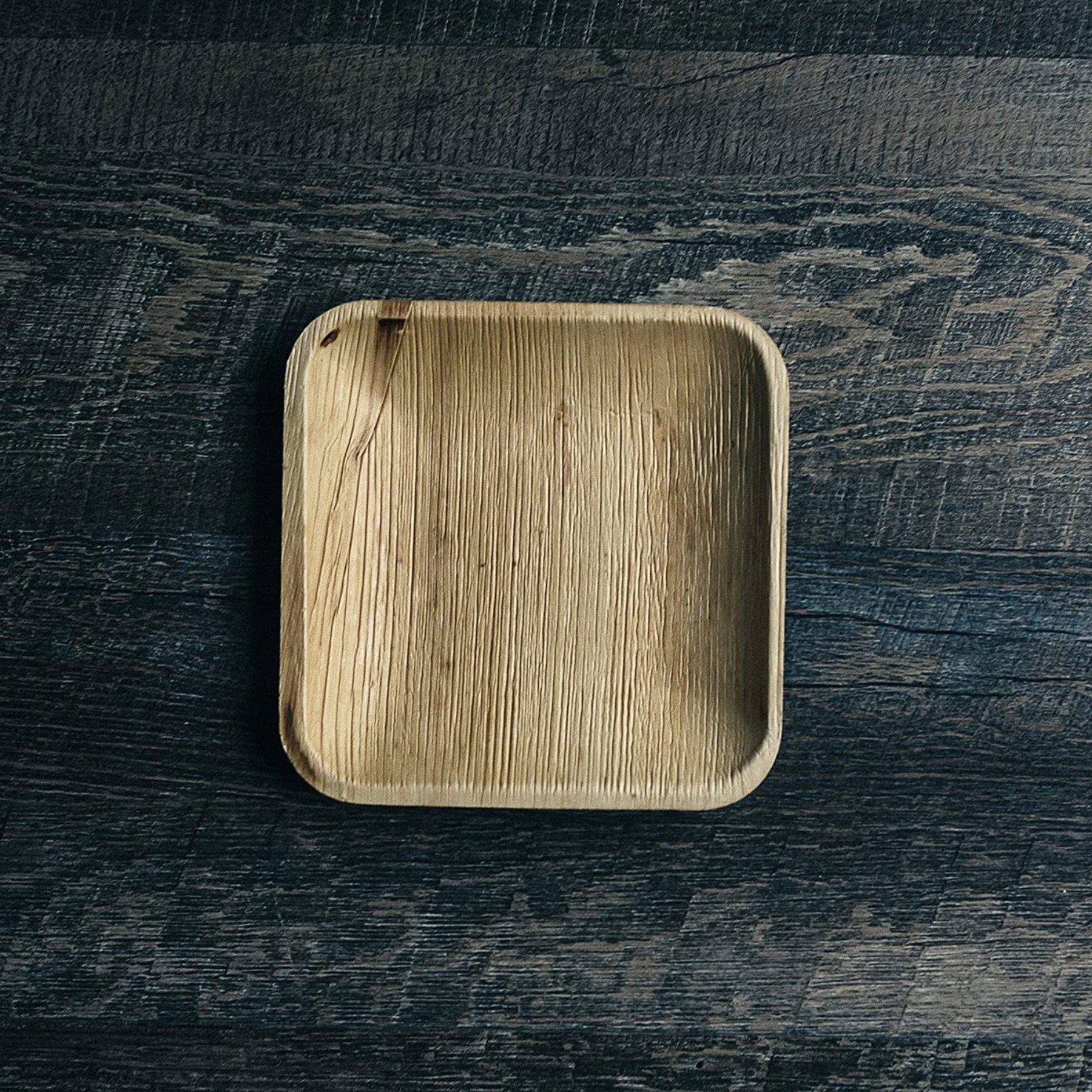 Single square bamboo plate on rustic wood background