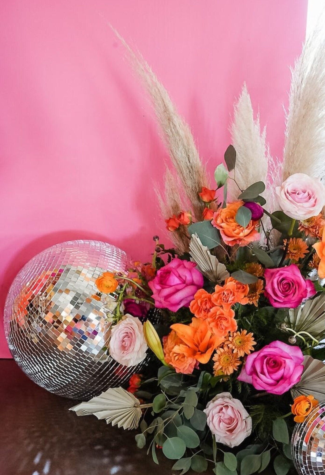 Silver disco ball styled with bright floral arrangement for event décor