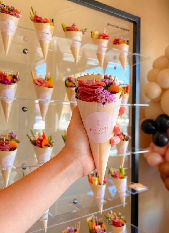 Guest holding large bamboo charcuterie cone filled with snacks