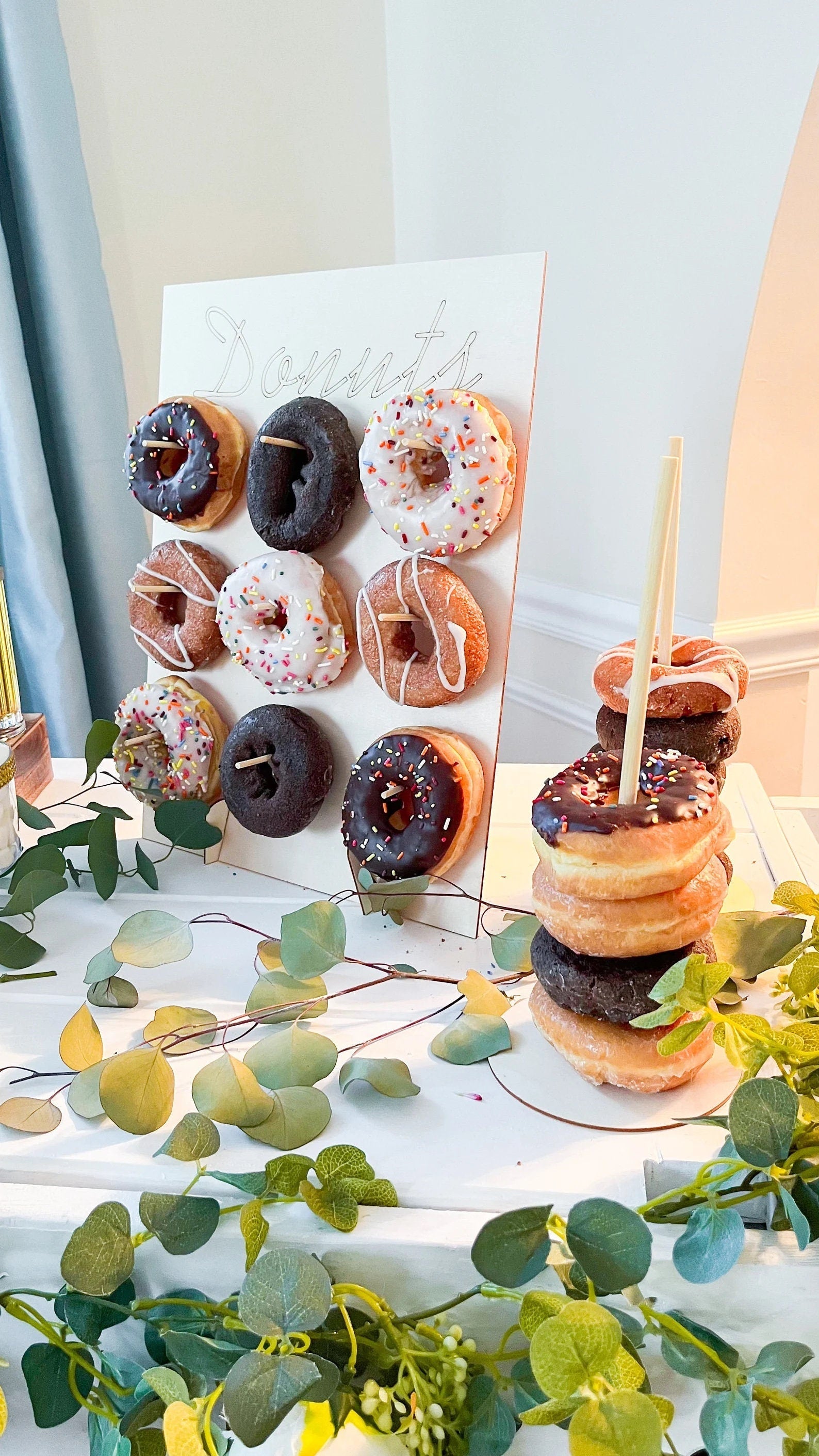 Donut wall stand styled on a table next to a vertical stacking donut stand