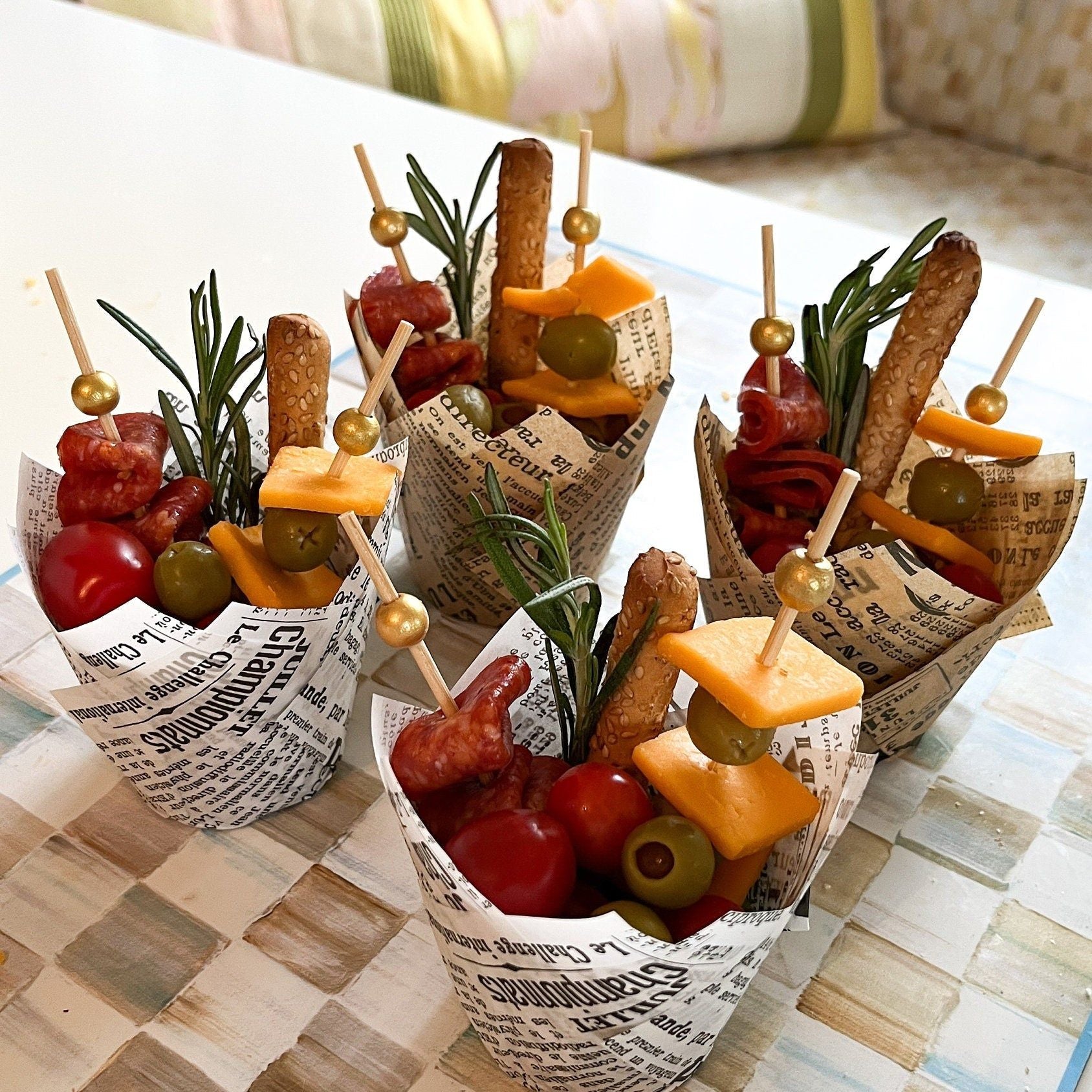 Empty newspaper design charcuterie paper cups stacked with fancy toothpicks ready for event catering