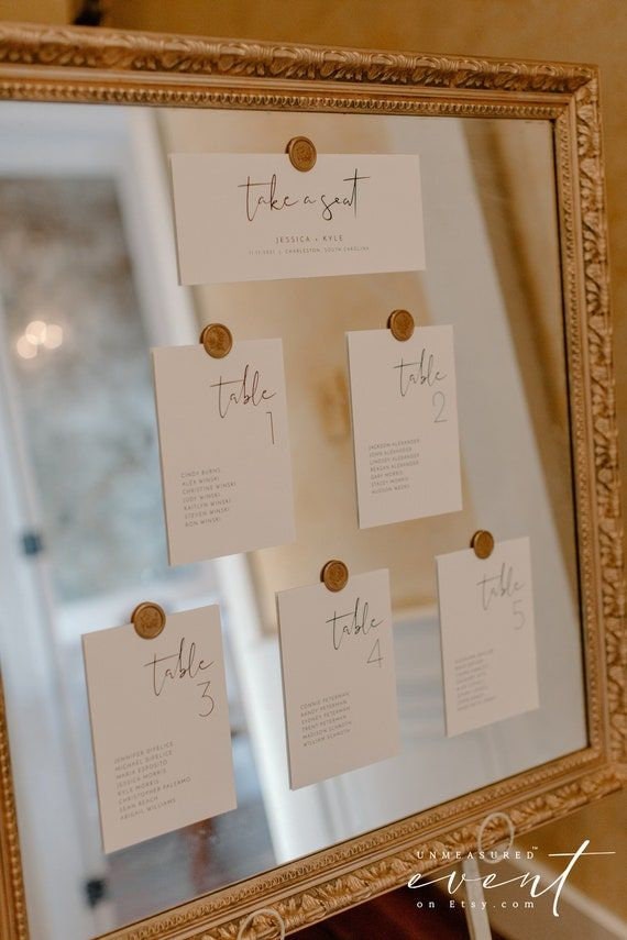 Hanging escort cards secured with assorted wax seal stickers and twine for a wedding display.