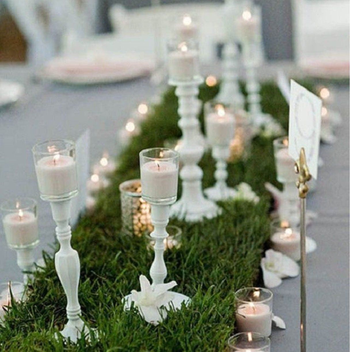 Faux grass table runner with white candlesticks and candles for wedding décor