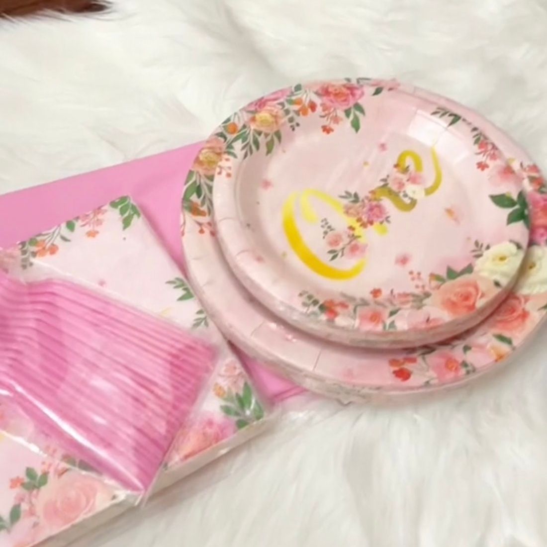 First birthday decor featuring pink tablecloth, gold accents, and themed party supplies