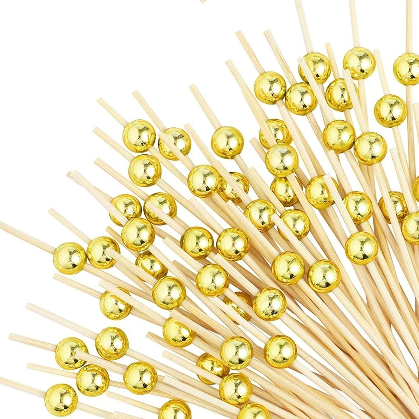 Gold fancy toothpicks skewering salmon appetizers on elegant formal table setting for sophisticated party presentation.