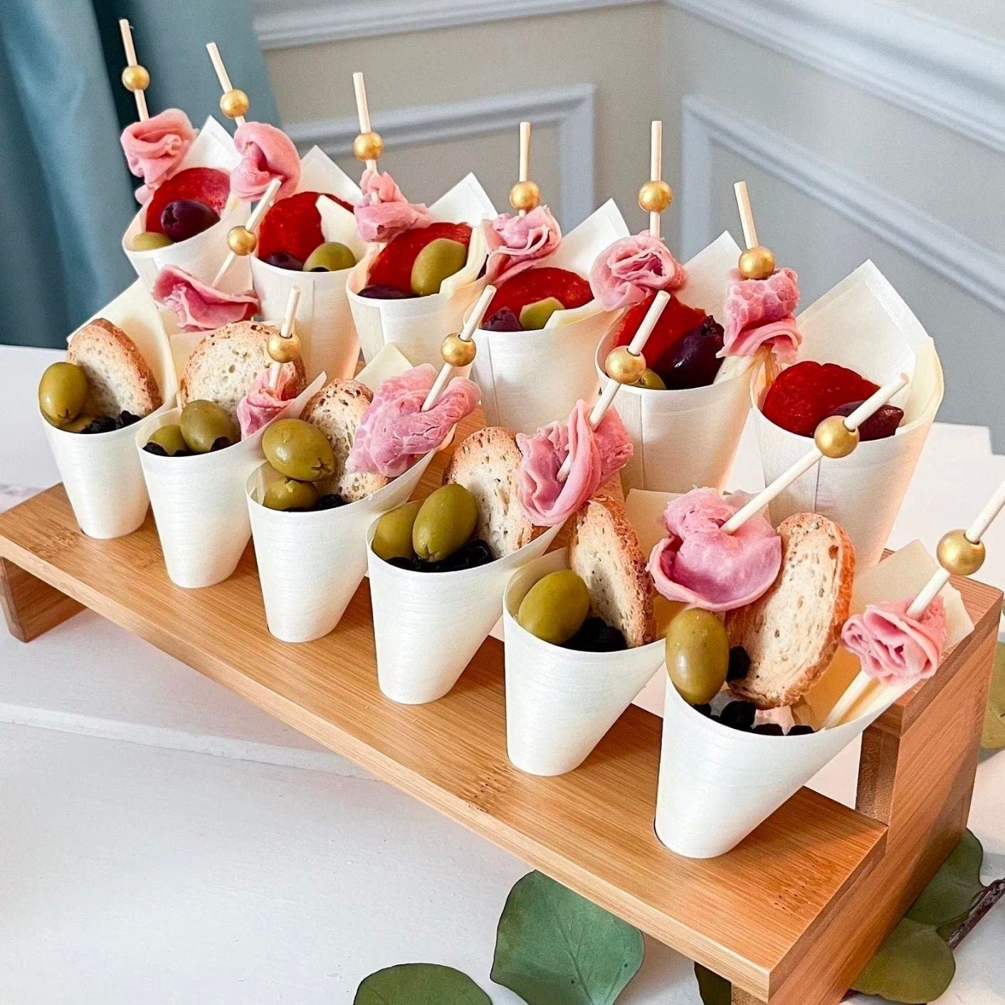 Charcuterie cones styled with fruits, meats, and gold toothpicks for events
