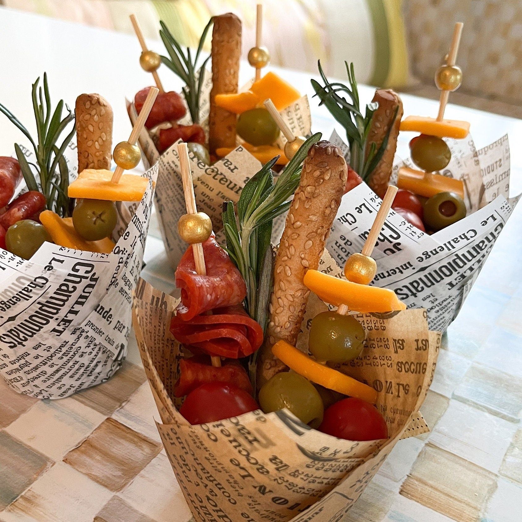 Grazing table display with newspaper charcuterie cups and matching toothpicks creating stylish food station