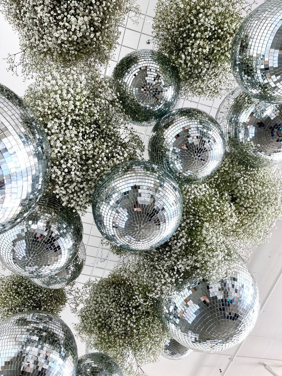 Silver mirror disco balls with baby’s breath florals hanging from ceiling