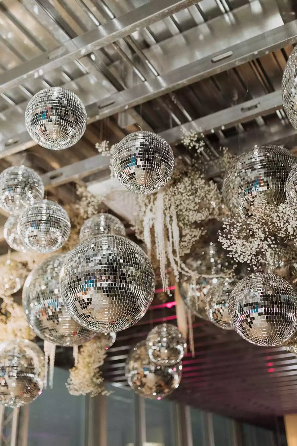 Multiple disco balls hanging in industrial venue with rope