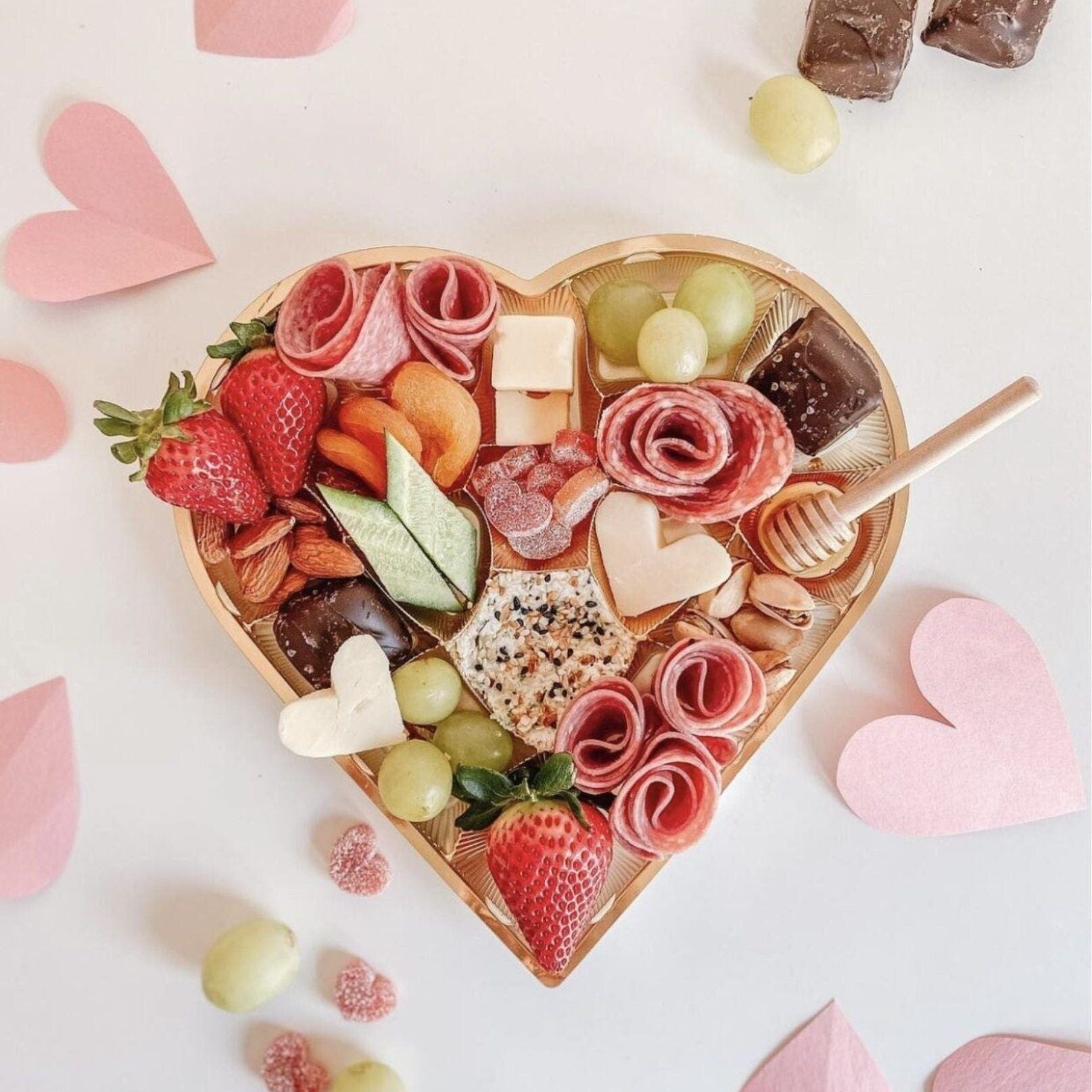 Romantic heart-shaped charcuterie board with chocolate dip, fruits, and desserts for special event