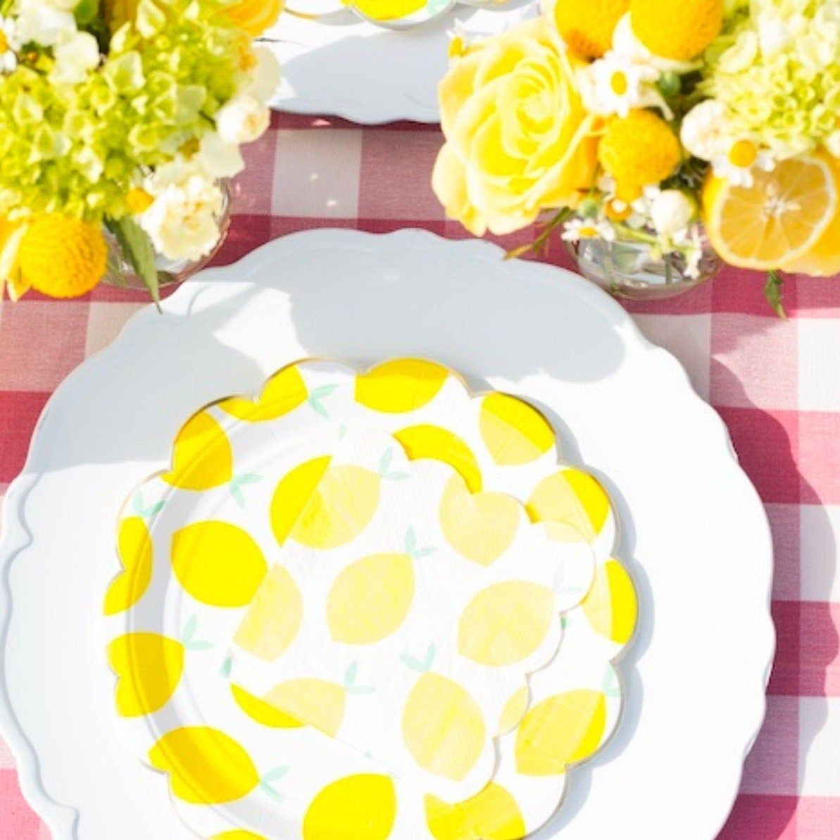 Lemon paper plates with floral centerpieces on outdoor summer table