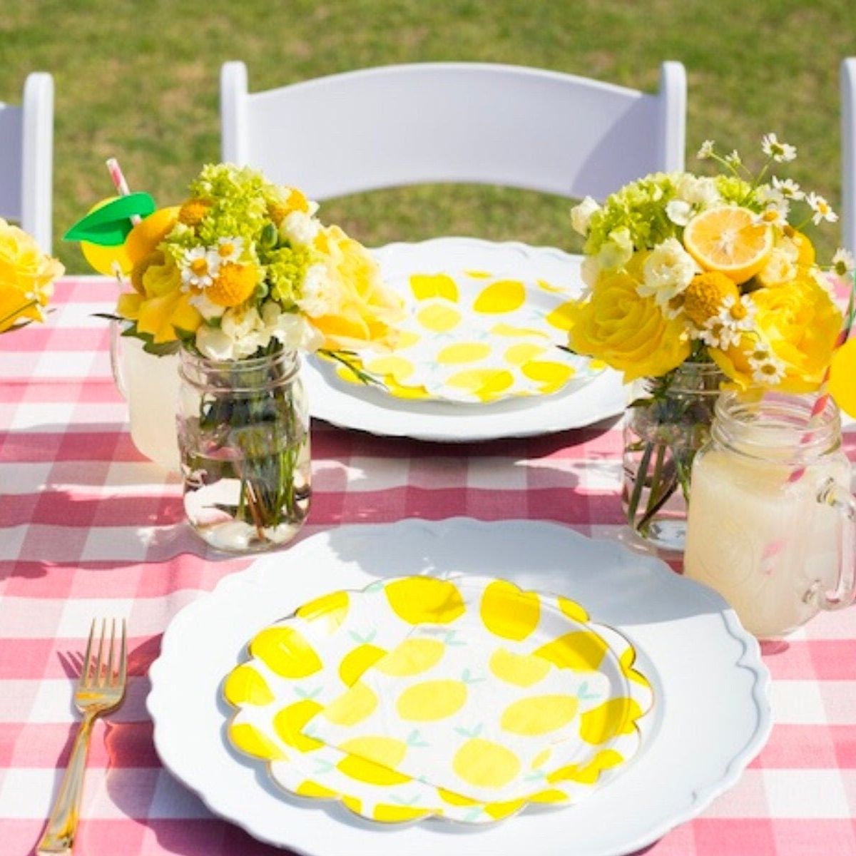 Outdoor picnic table set with lemon plates, napkins, and floral decorations