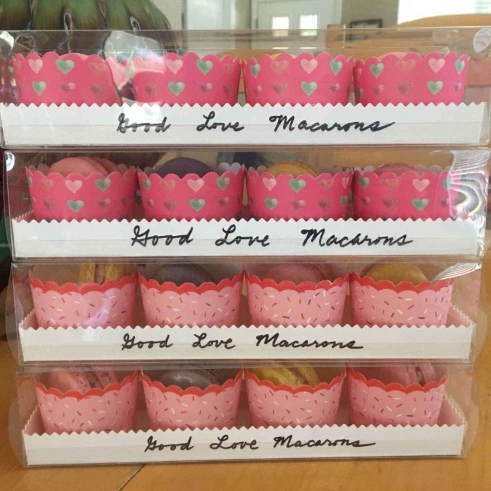 Four-tier display of white macaroon boxes with pink liners ready for favors