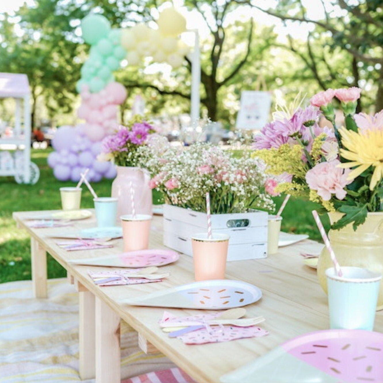 Outdoor party table setup with pastel ice cream party tableware and flowers