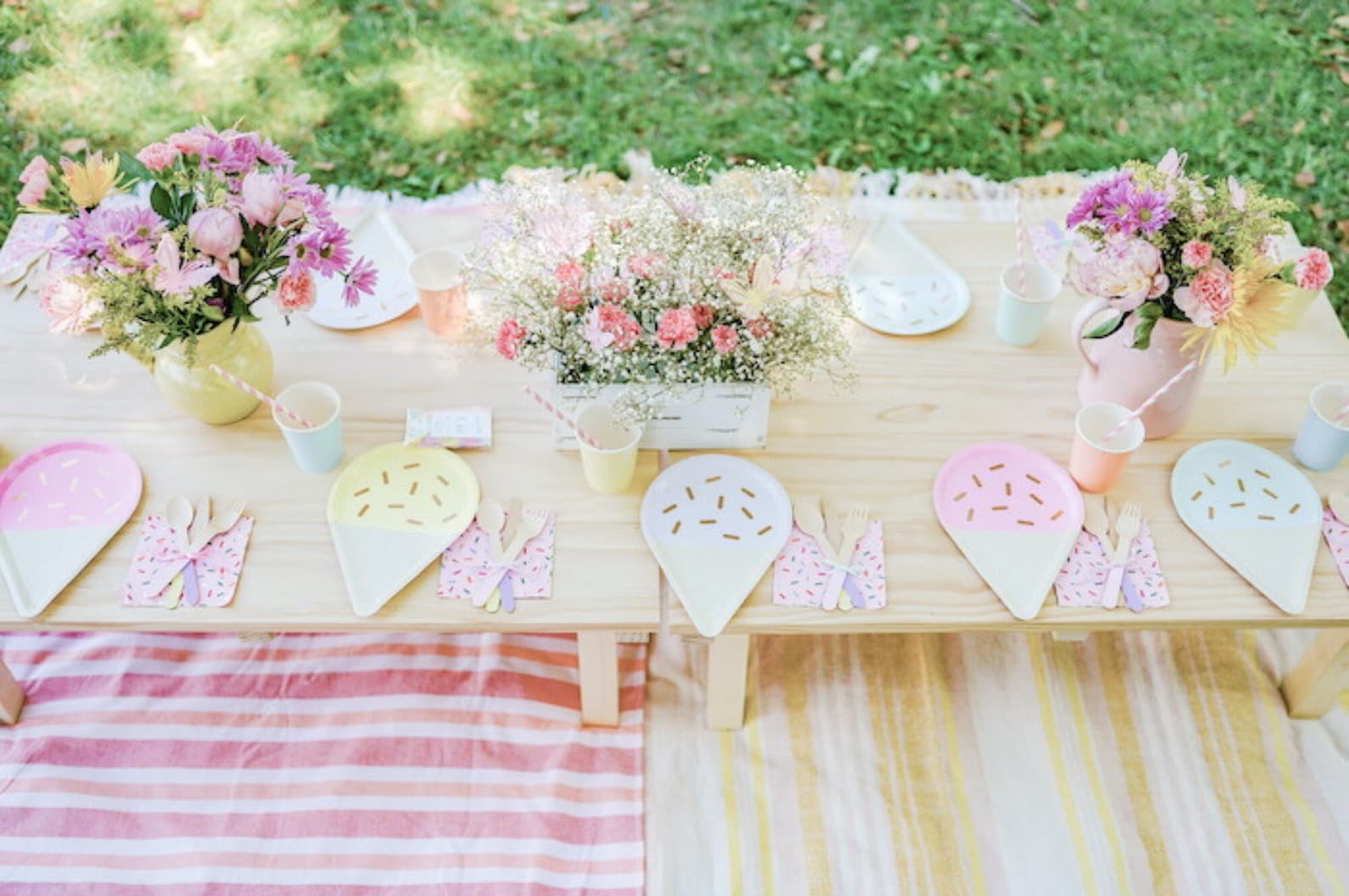 Outdoor party table setup with pastel ice cream party tableware and flowers