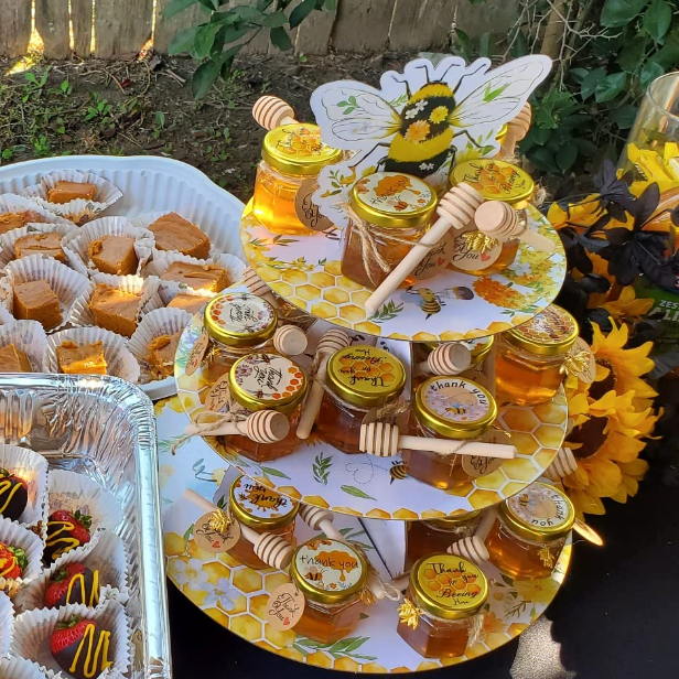 A beautifully arranged set of mini honey jars with personalized tags as party favors at a baby shower.