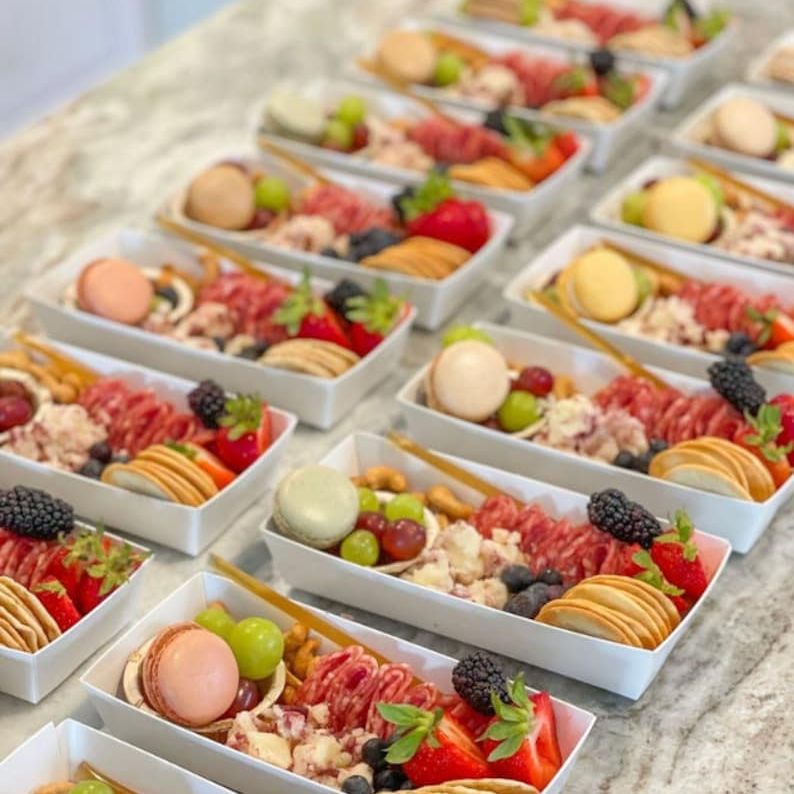 Colorful grazing boxes with fruits, meats, and cheeses for event catering.