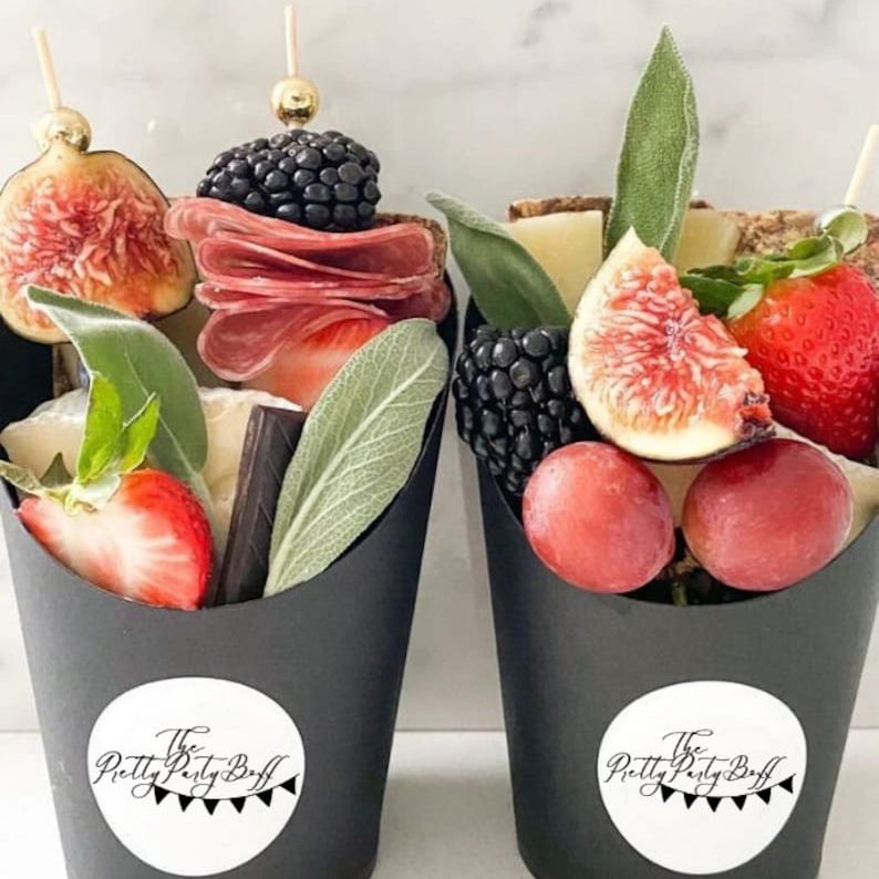 Multiple charcuterie cups with meats, cheeses, and fruit styled for events.