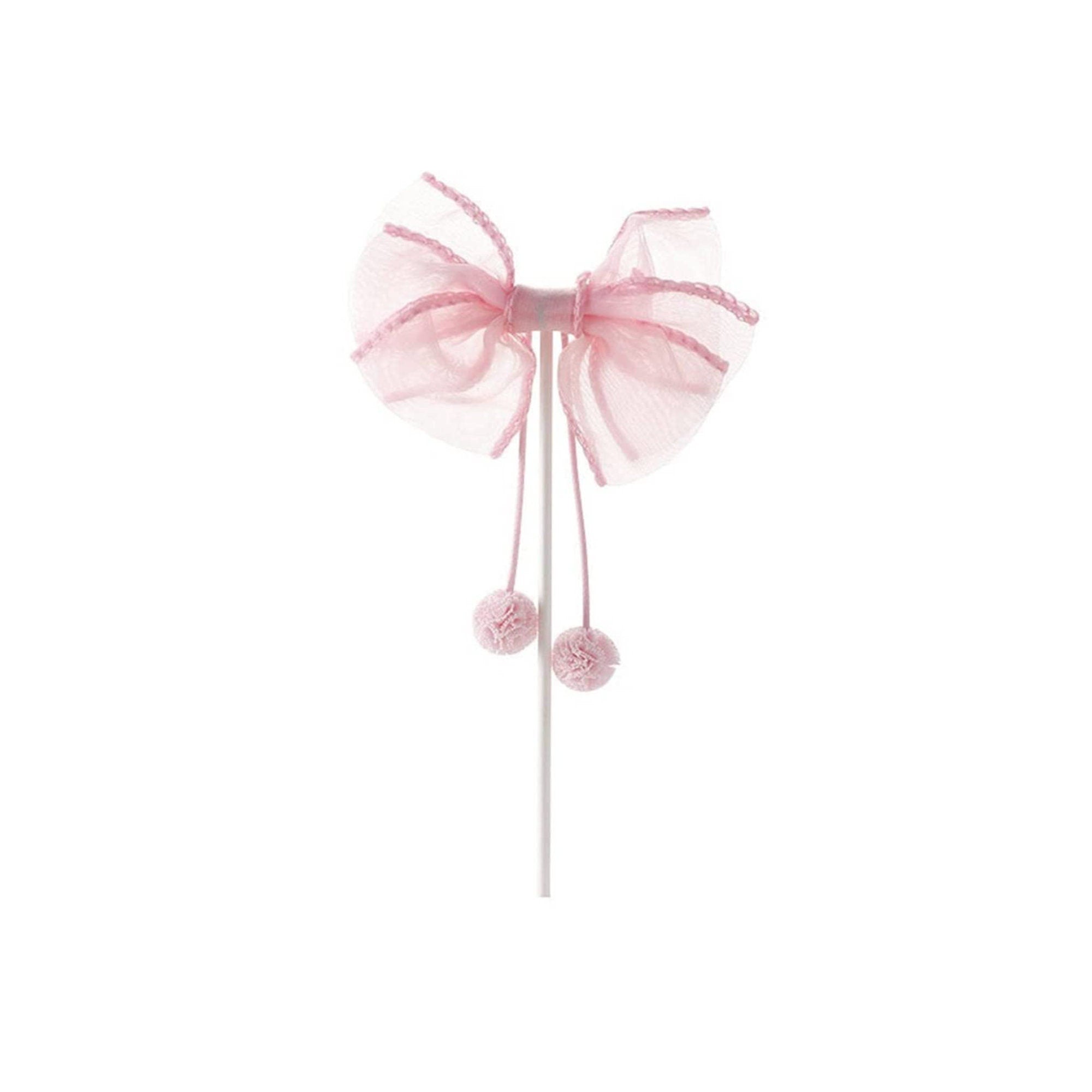 Pink ribbon bow cake topper with pom-pom tails on food-safe pick