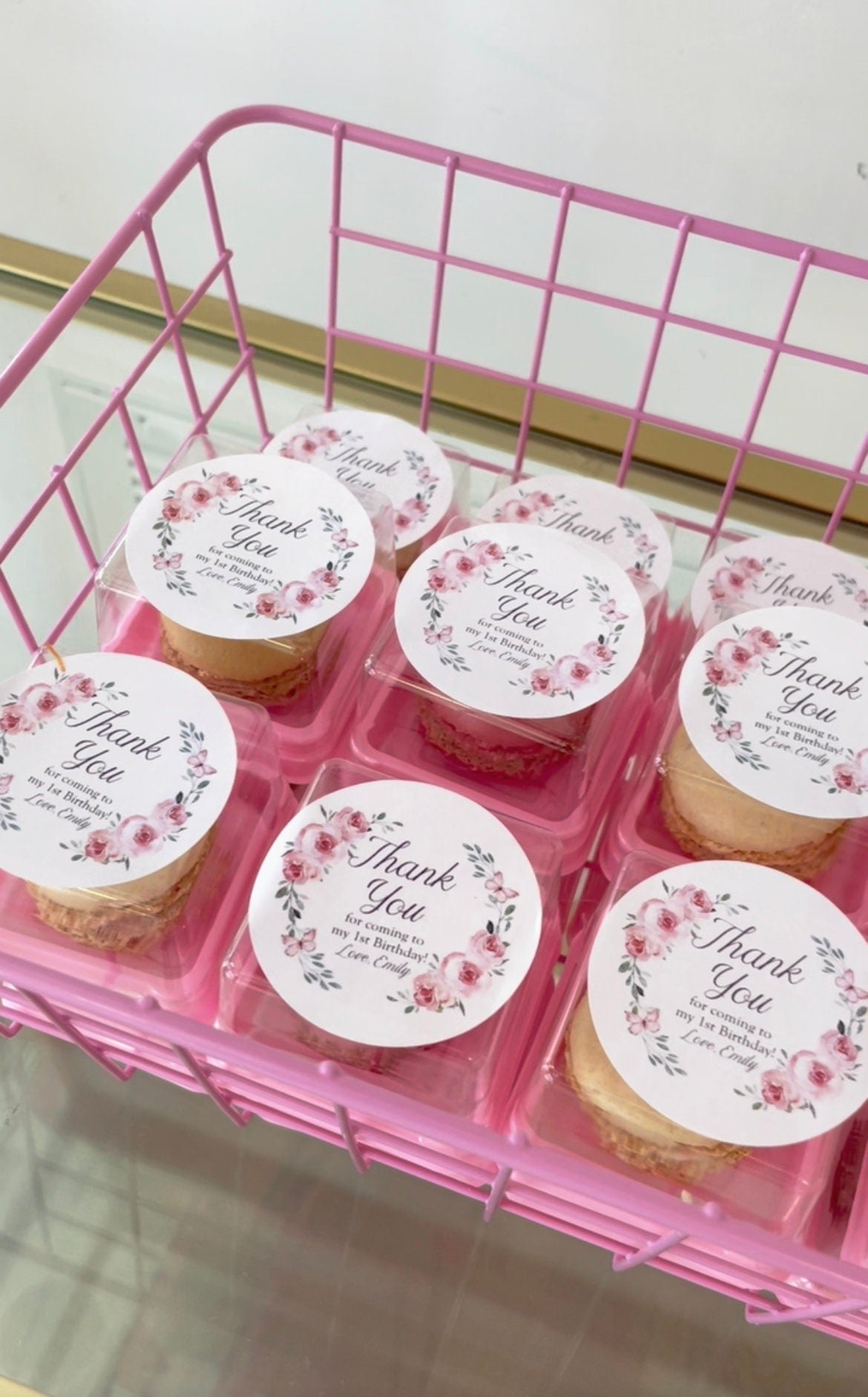 Shelf basket filled with pink dome and square macaroon boxes, showcasing treats in clear favor boxes.