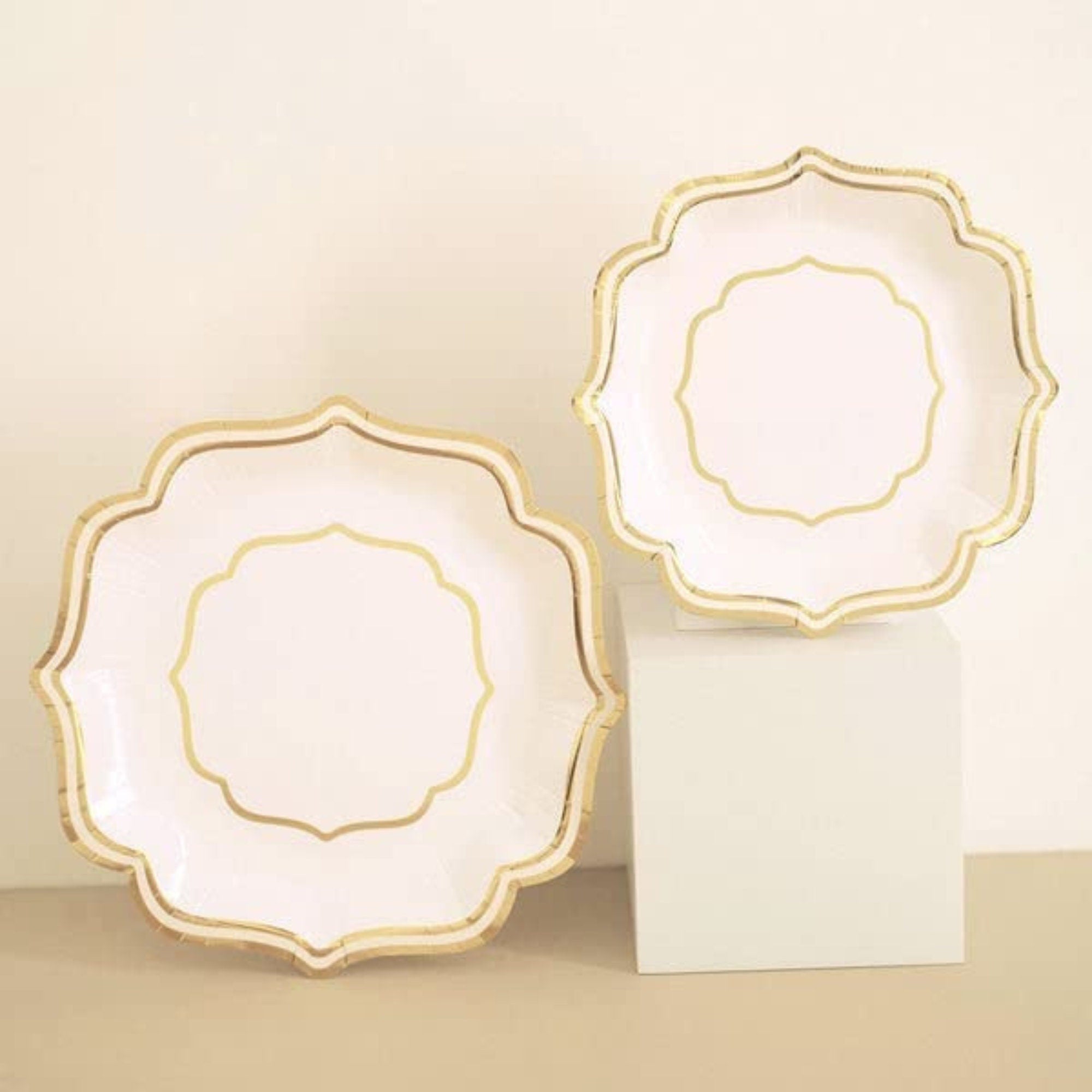 Stacked pink and gold plates in dinner and salad sizes against neutral background