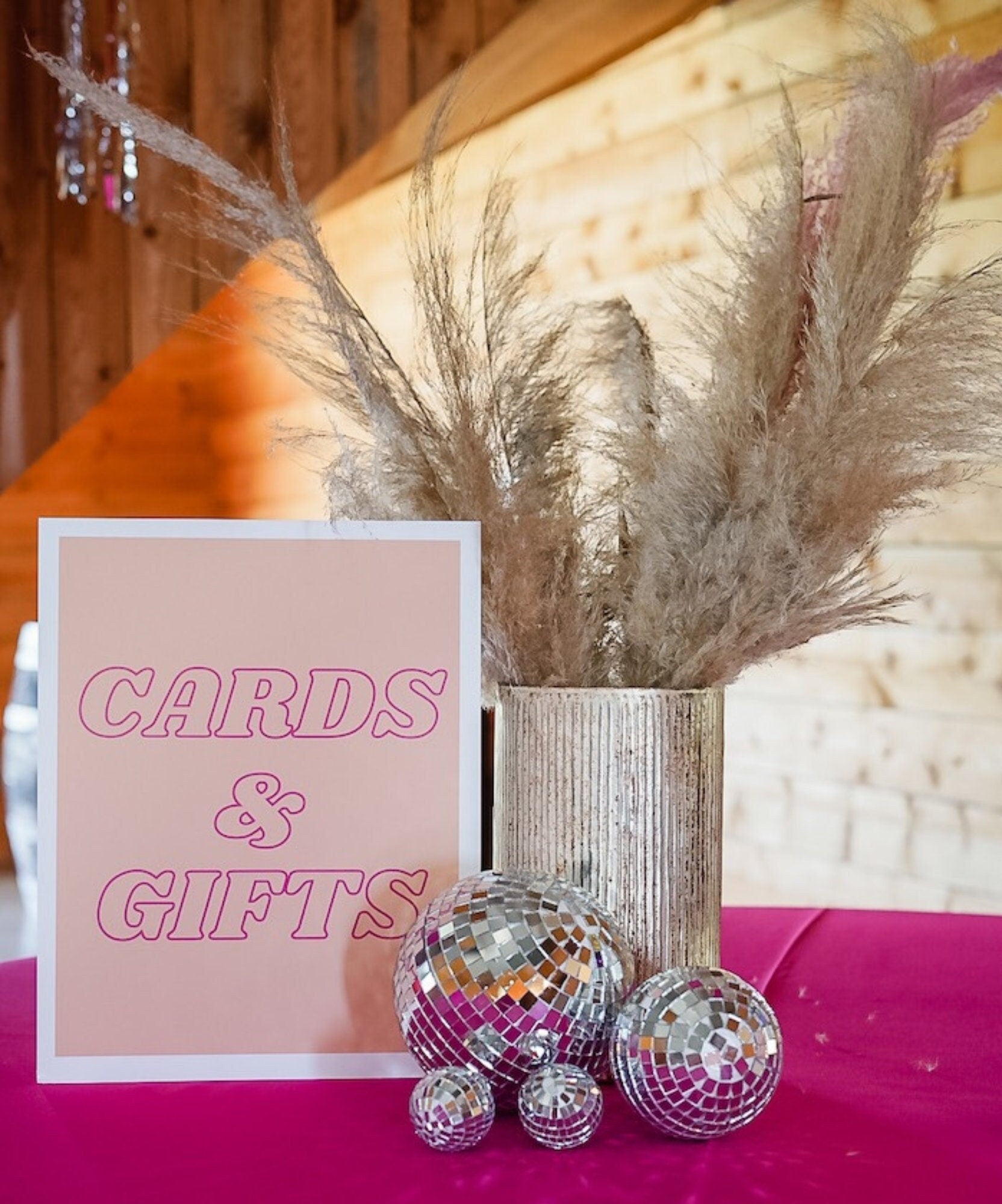 Small silver disco balls styled with pampas grass at gift table