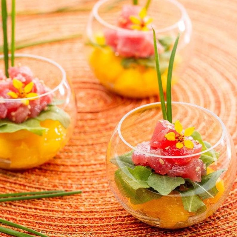 Trio of round acrylic bowls filled with colorful salad tastings on woven mat