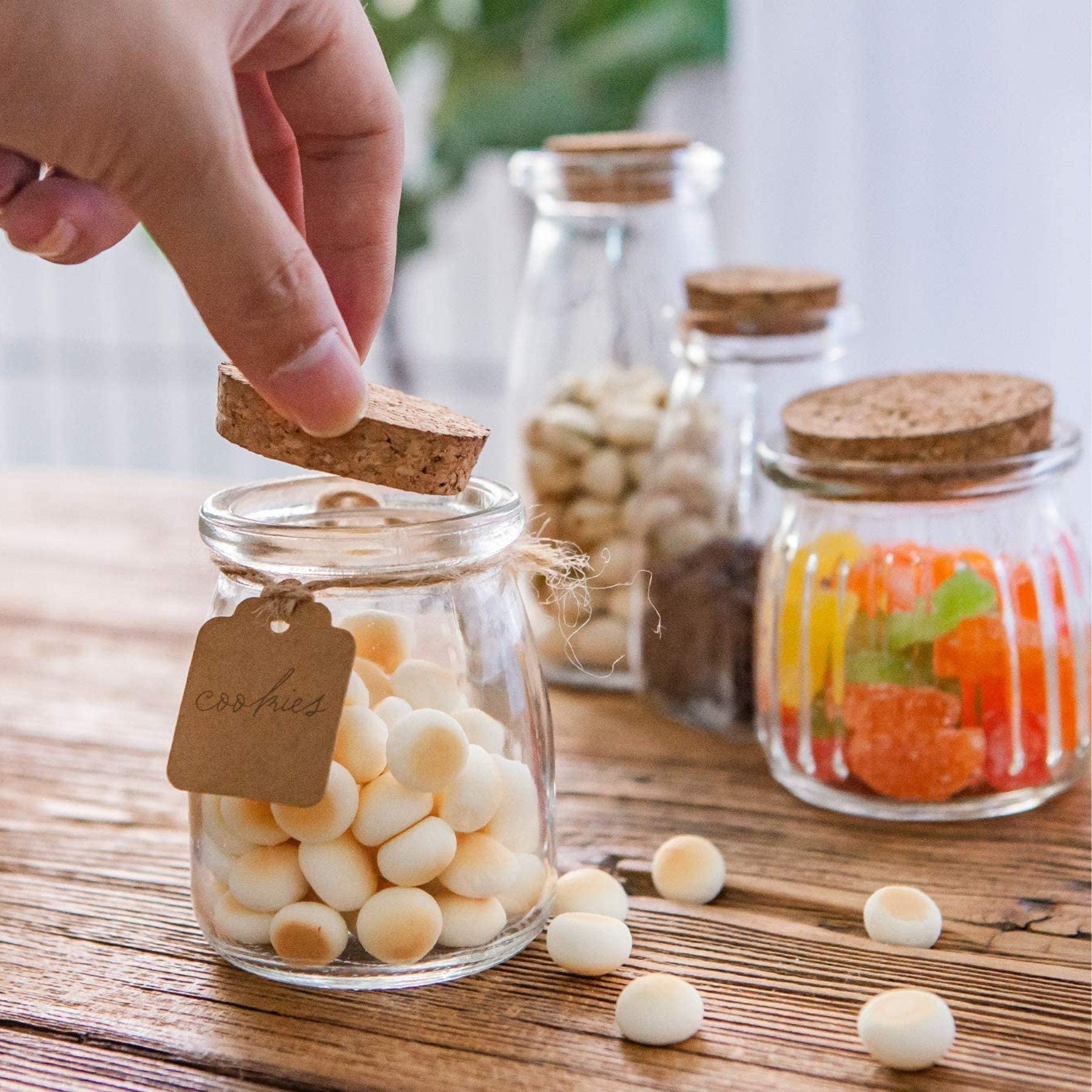 Assorted small jars filled with candy and spices, cork lids tied with twine