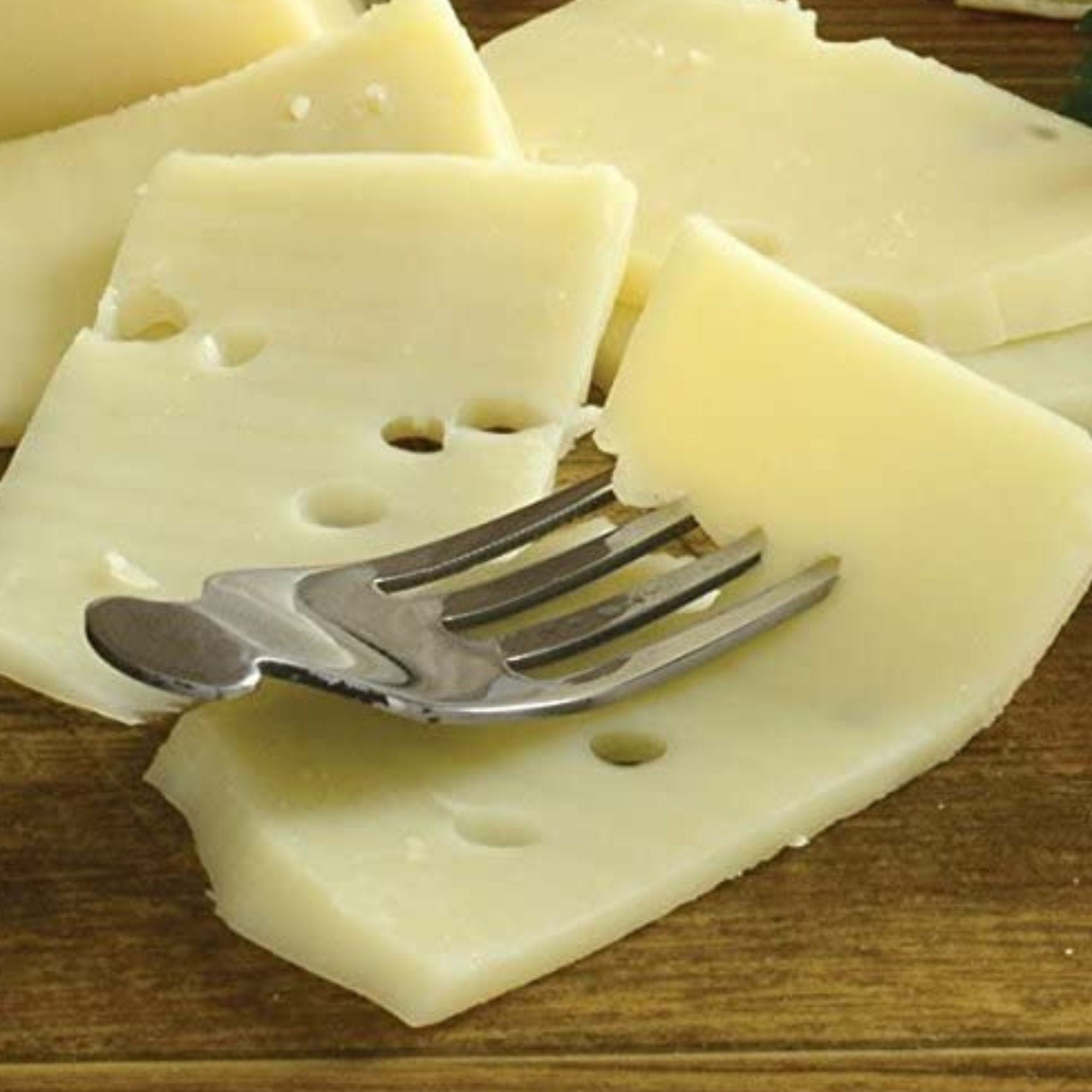 Cheese fork marker resting on sliced Swiss cheese