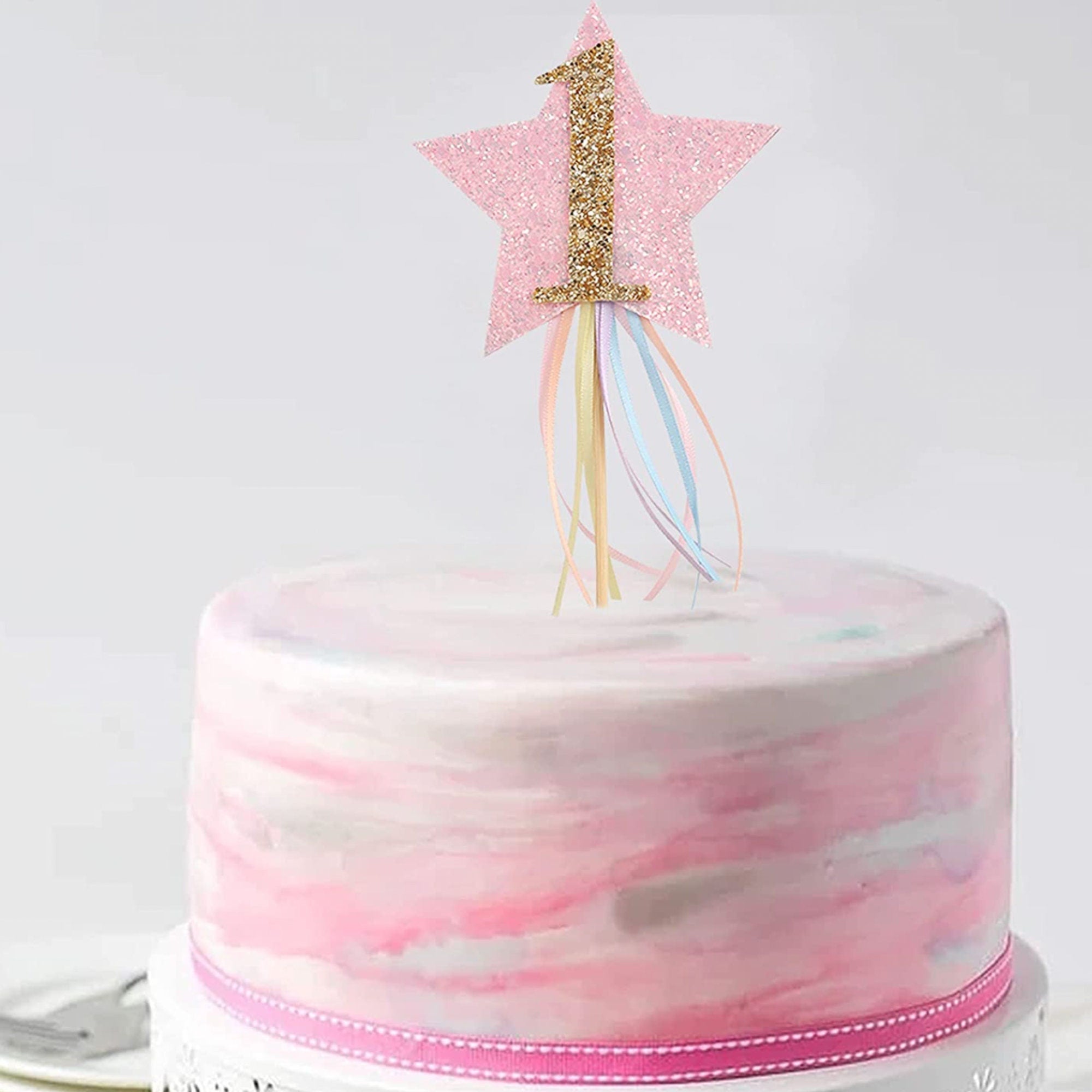 Flat lay view of birthday cake topper showing gold star with colorful ribbon streamers