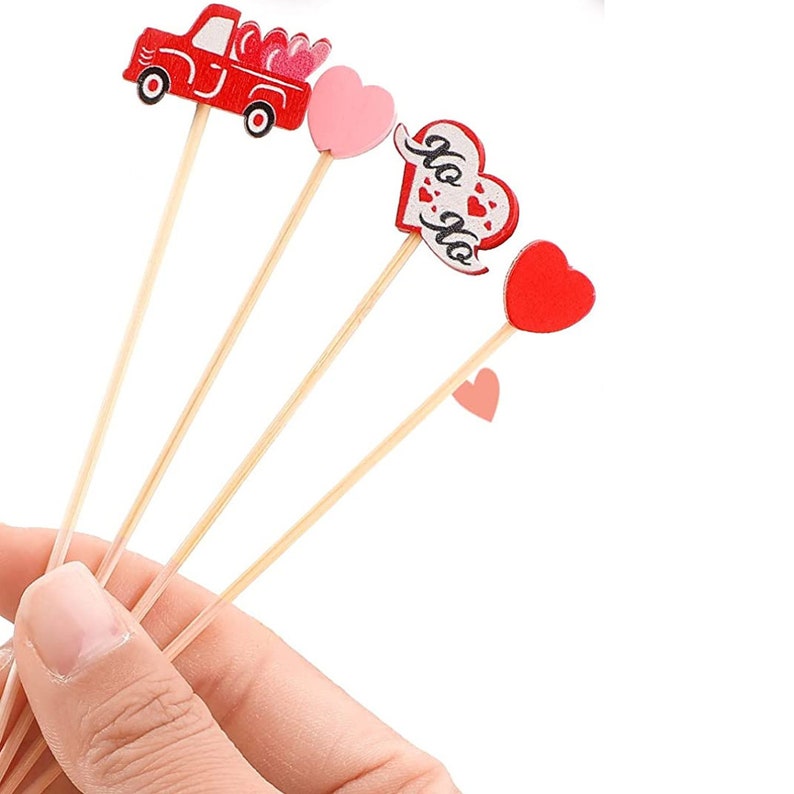 Heart shaped charcuterie toothpicks with red, pink, and XO toppers held in hand