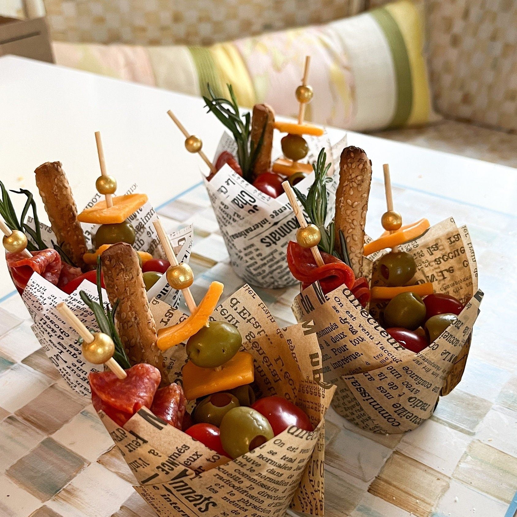 Close-up of black and white newspaper design charcuterie cup with decorative gold toothpick detail