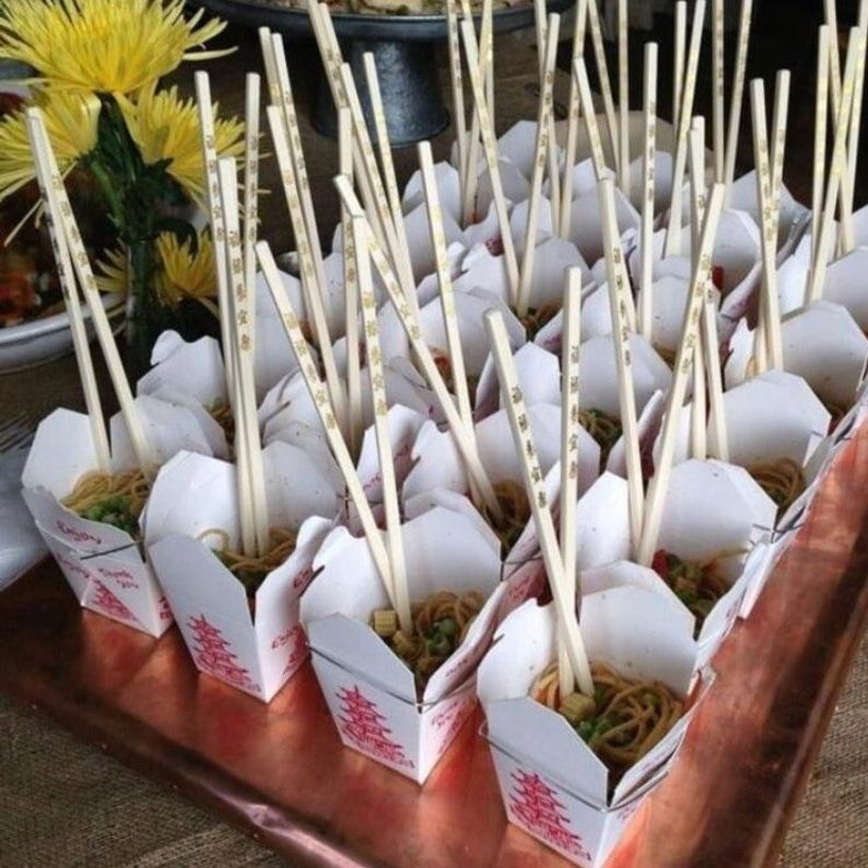 Tray of white Chinese take out boxes with wooden chopsticks filled with noodles for catering buffet.