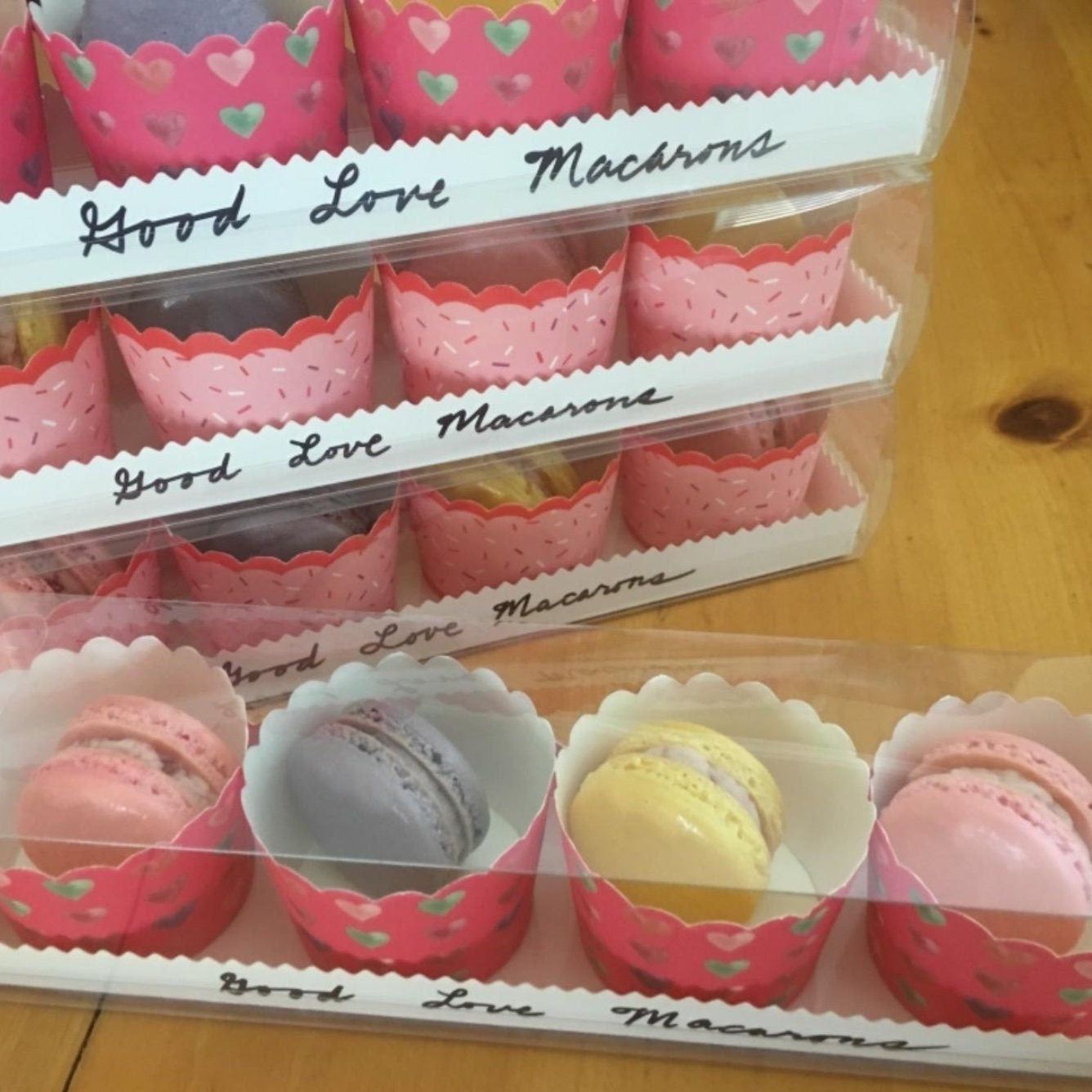 Stacked white macaroon boxes filled with pink liners and assorted macarons