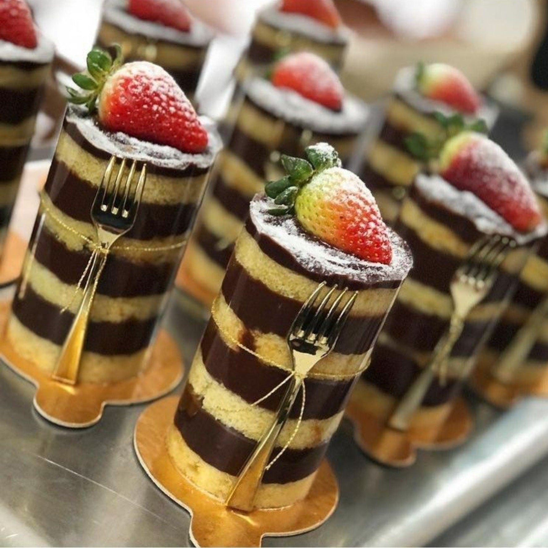 Gold mini fork resting beside a wrapped cake on a dessert table, highlighting stylish and practical presentation.