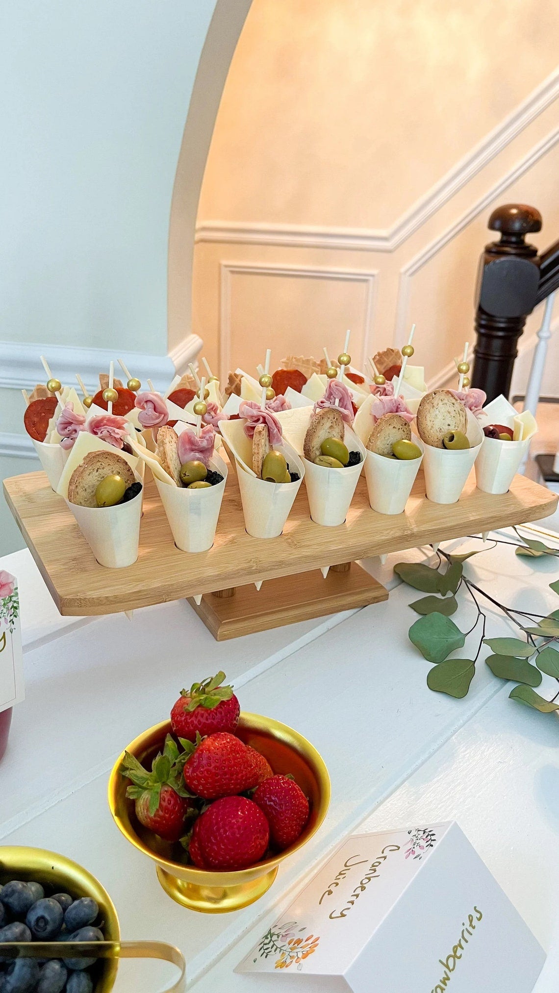 Charcuterie cups on a bamboo display stand. Disposable wooden cones for elegant catering or a bridal shower.