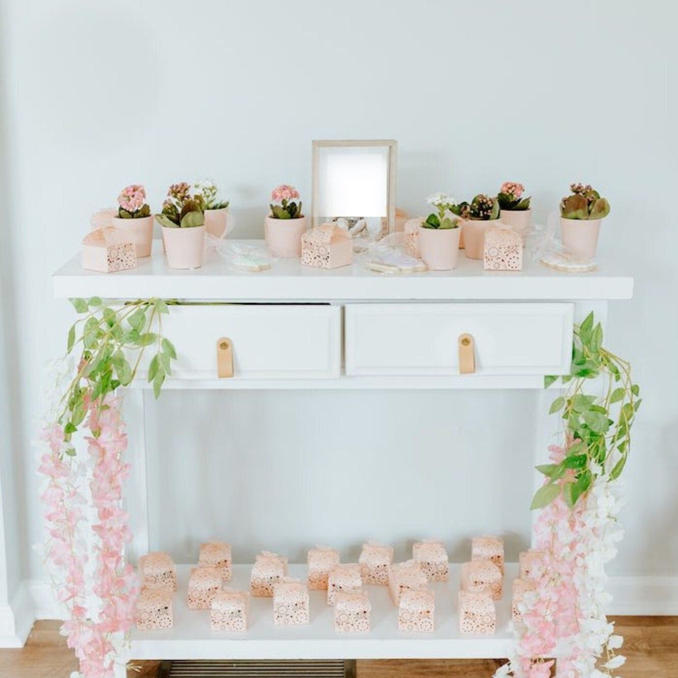 Close-up of favor table with pink butterfly boxes, flowers, and small gifts